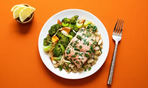 Healthy salmon + veggies + quinoa dish I made for lunch on a orange background for contrast.